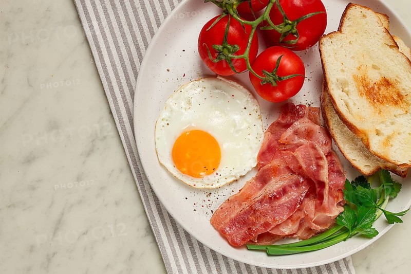 Breakfast, fried egg, bacon and bread, with cherry, on a light background, homemade, no people
