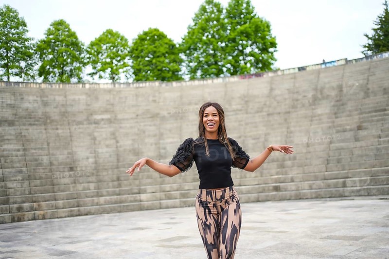 Horizontal photo with copy space of a happy hispanic woman dancing salsa in a public park