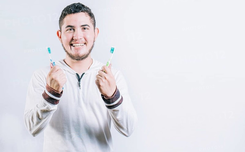 Teenager holding two toothbrushes isolated. Oral health concept. Toothbrush change concept