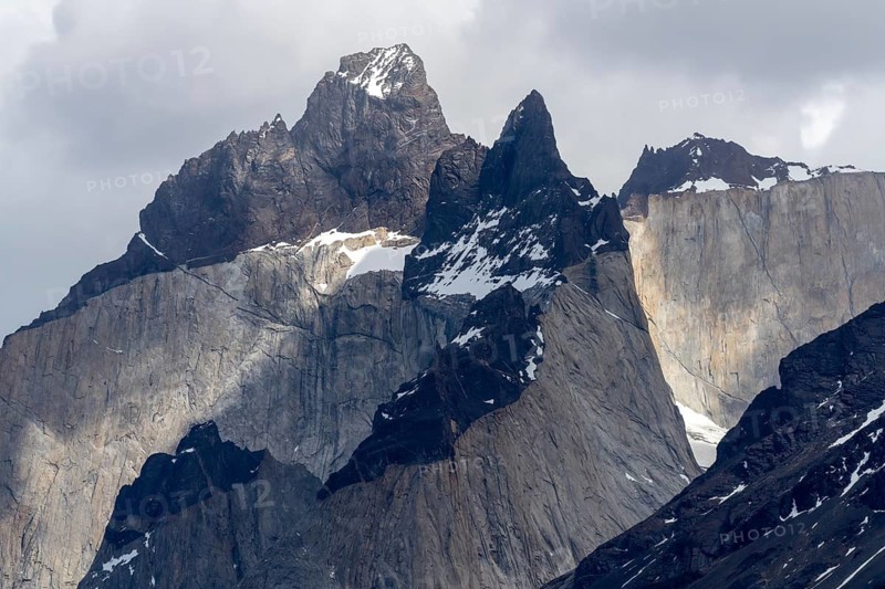 Cuernos del Paine, rocky peaks with dark slate tip and light granite base, residual snow on the flanks under cloudy sky, Torres del Paine National Park, Patagonia, Chile