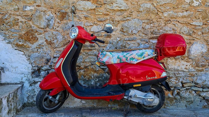 Vespa, Red retro scooter parked at an old stone wall, sunny day, Symi town, Symi, Dodecanese, Greek Islands, Greece