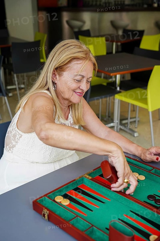 A woman plays backgammon, showcasing focus and enjoyment The colorful board and pieces create a vibrant scene in a modern setting, emphasizing social and strategic interaction