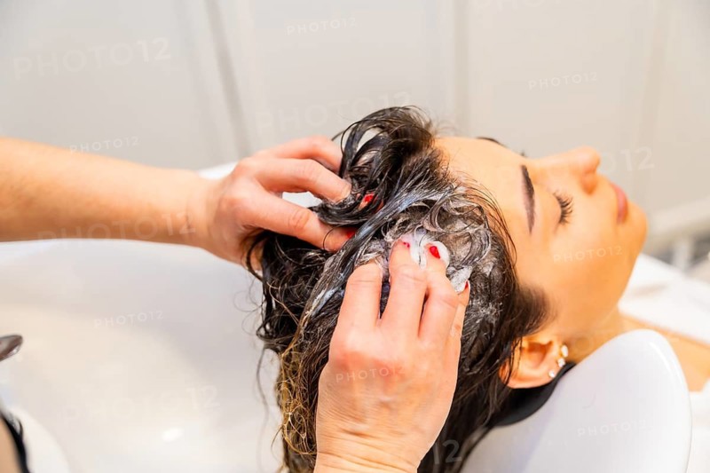 Top view close-up of the hands of hairdresser washing the damaged hair of a woman