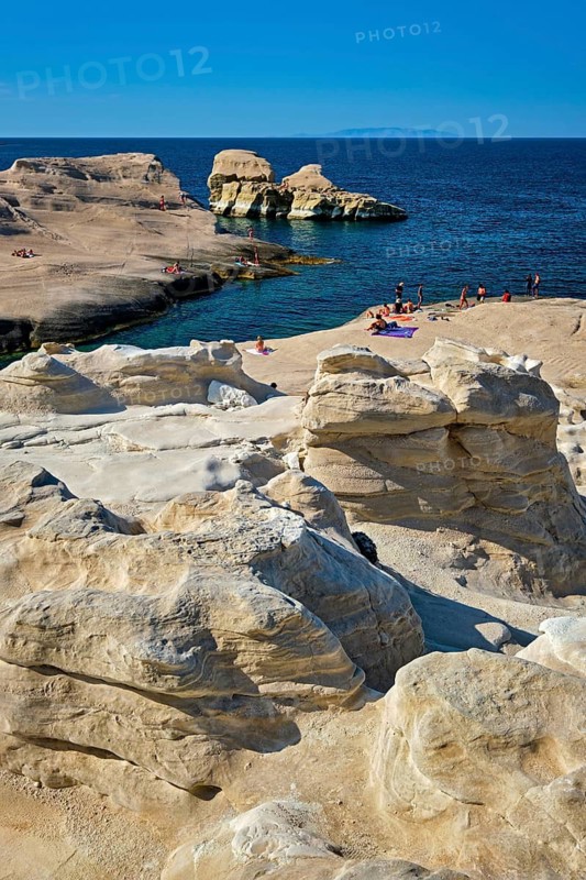 White rocks of famous tourist attraction of Milos island Sarakiniko beach with tourist relax and Aegean sea, Milos island, Greece