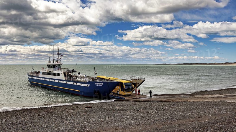 Ferry on a pebble beach in front of a cloudy sky and calm sea, ready for departure, The car ferry at Puerto Natales in Patagonia Chile