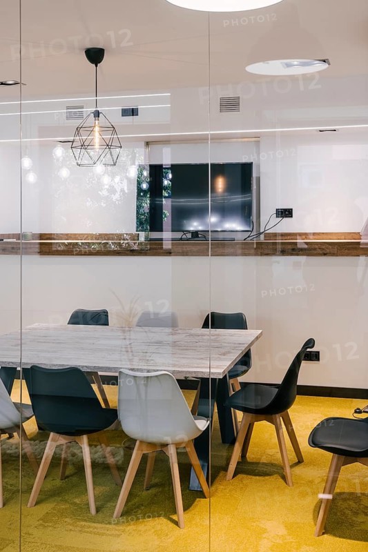 Minimalist meeting room with glass walls. Marble table, modern chairs, and a decorative geometric lamp