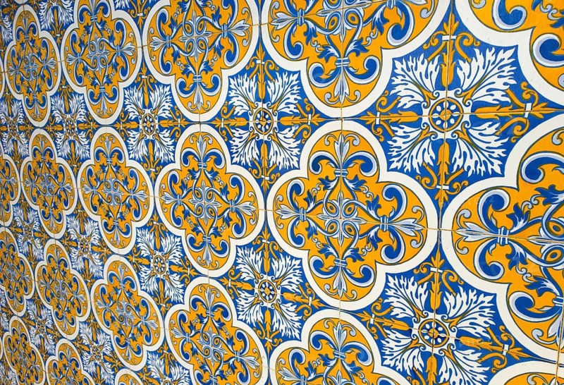 Decorative tiles with blue and yellow patterns on a wall, showing a traditional and symmetrical design, Azulejos, Portugal