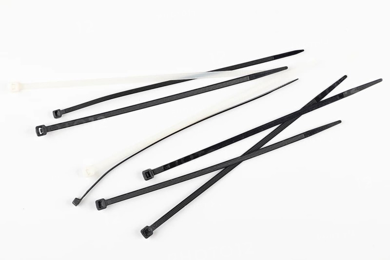 Several black and white cable ties lie loose on a white background