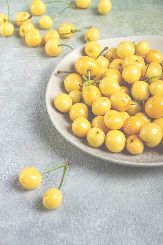 Yellow cherry, cherry berry, scattered on a plate, top view, no people