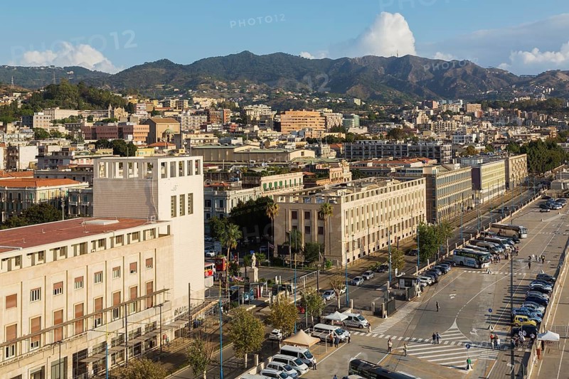 High angle view of parking lot with parked sightseeing and tour buses and Messina city skyline, Sicily, Italy