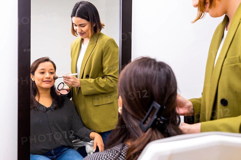 A makeup artist applies cosmetics to a woman during an image consulting session. The bright, professional setting emphasizes personal care, beauty enhancement, and style advice