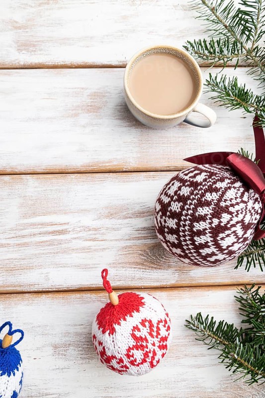 Christmas or New Year composition. Decorations, knitted balls, fir and spruce branches, cup of coffee, on a white wooden background. Top view, copy space, flat lay