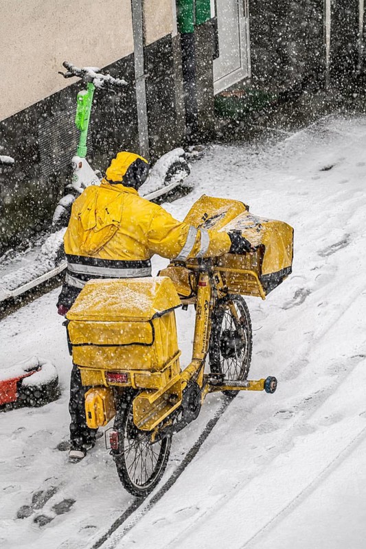 Winter weather, heavy snowfall, city centre traffic, postman with bicycle in the snow, Essen, North Rhine-Westphalia, Germany