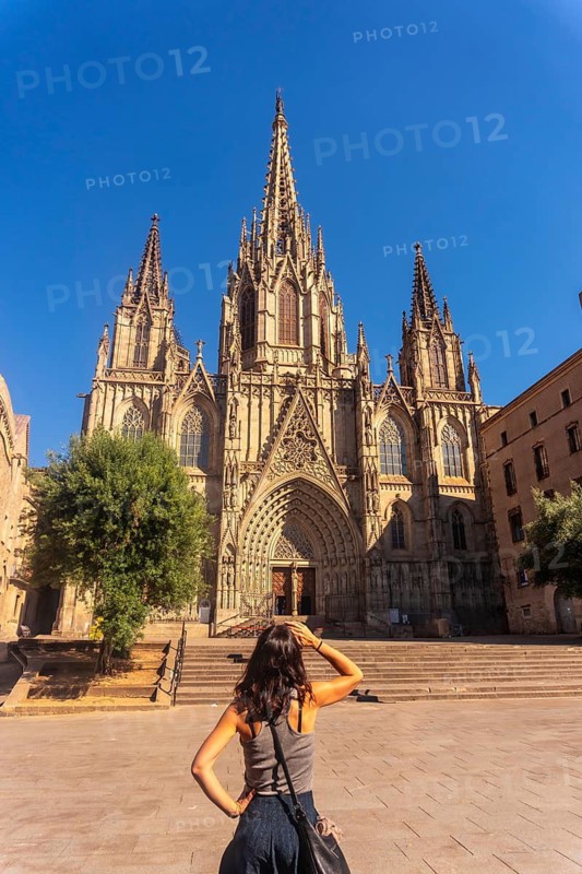 Young woman contemplating the stunning gothic architecture of the barcelona cathedral on a sunny summer day, embracing the rich cultural heritage of catalonia