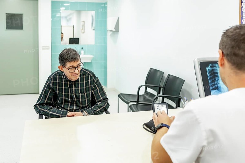 A mental health professional consults with a patient in a mental health residence, discussing care and treatment in a calm, clean environment with medical tools visible