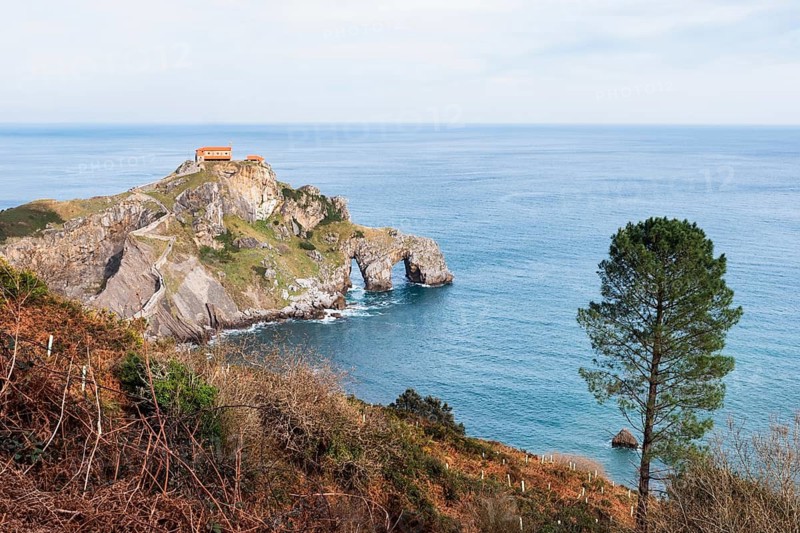 Scenic capture of Gaztelugatxe, showcasing its rugged cliffs and the historic Saint John the Baptist hermitage that dates back to the 10th century, set against the backdrop of the Bay of Biscay in Bermeo, Basque Country