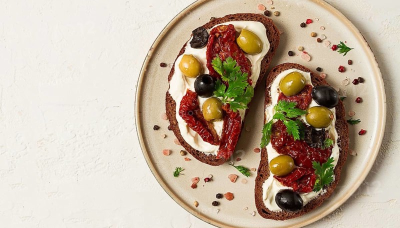 Breakfast, sandwiches with dried tomatoes, olives, and cheese cream, top view