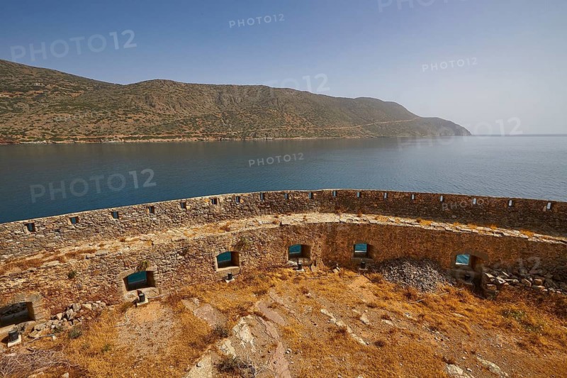 Ancient stone wall overlooking a calm sea with mountains in the background under a clear blue sky, Venetian Sea Fortress, Leprosy Island, Spinalonga, Elounda Bay, Mirabello Bay, East Crete, Crete, Greek Islands, Greece