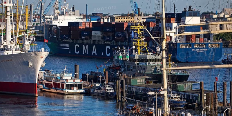 Container ship of the shipping company CMA CGM with many different ships in the port of Hamburg, Germany