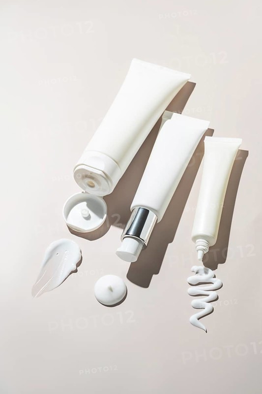 Aesthetic arrangement of cosmetic packaging showcasing elegant textures and soft creams. The tubes are placed on a neutral background, creating a minimalist and soothing visual