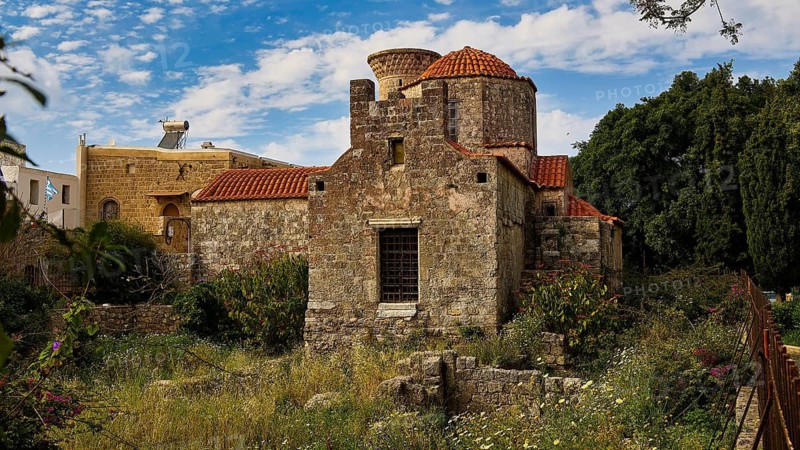 Old church with tiled roof, surrounded by green meadow and historic walls, Rhodes Old Town, Rhodes, Dodecanese, Greek Islands, Greece