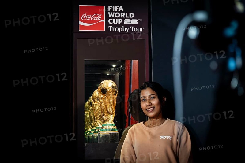 A football fan poses for a photograph with the original FIFA World Cup 2026 Trophy during the official India tour in Guwahati, Assam, India, on January 13, 2026