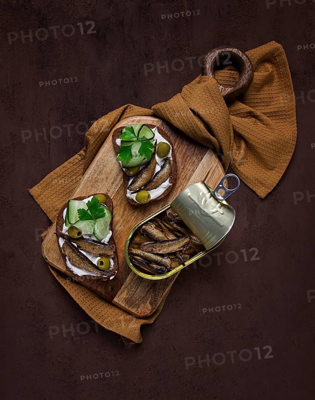 Sandwiches, black bread with sprats, cream cheese, cucumbers, on a cutting board, top view, close-up, no people