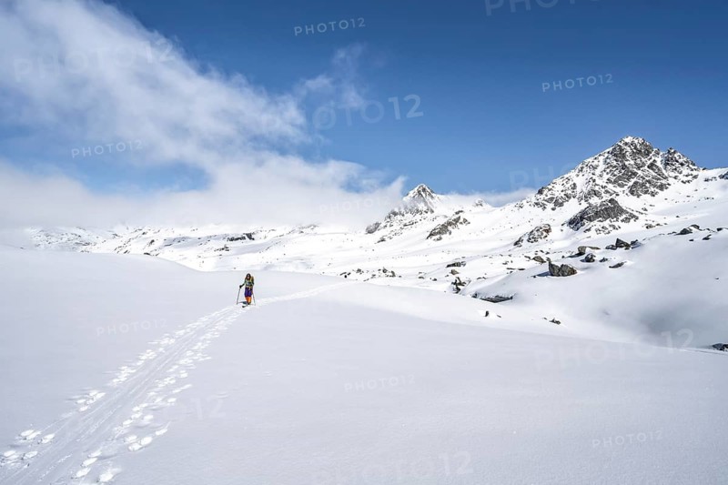 Ski tourer ascending through picturesque snow-covered mountain landscape with peaks, ascent to the summit of Kesch Pitschen, Bündner Haute Route ski tour, Albula Alps, Rhaetian Alps, Grisons, Eastern Switzerland, Switzerland
