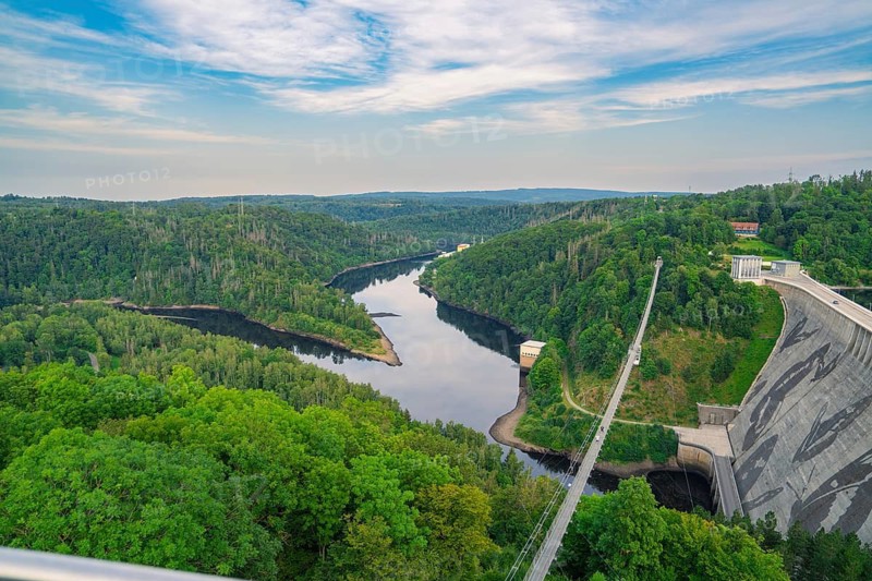 Extensive panorama of a green river landscape with dense forest under a blue sky and clouds, Rappbodetalsperre, Harz Mountains, Germany