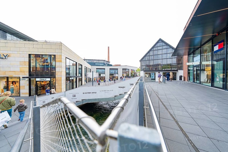 Modern urban area with glass-fronted shops and a small bridge, Outlet City Metzingen, Germany