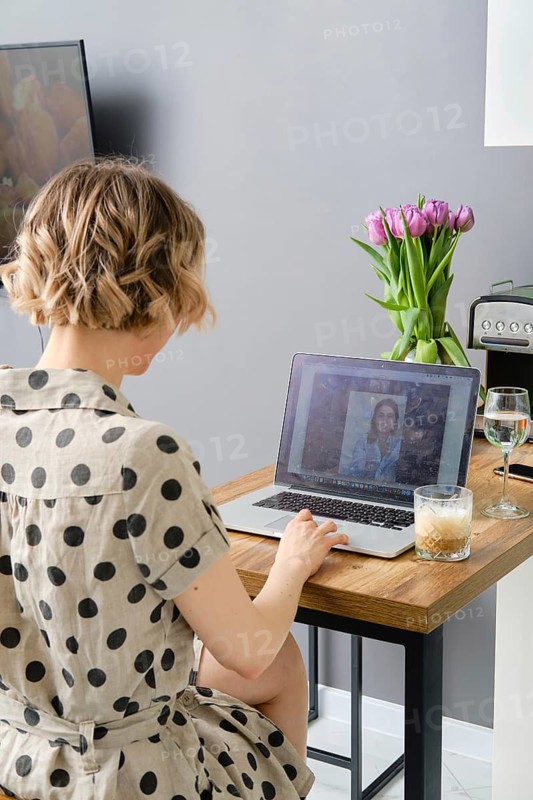 Back view of a woman making video call to business partner using laptop, looking at screen with virtual web chat