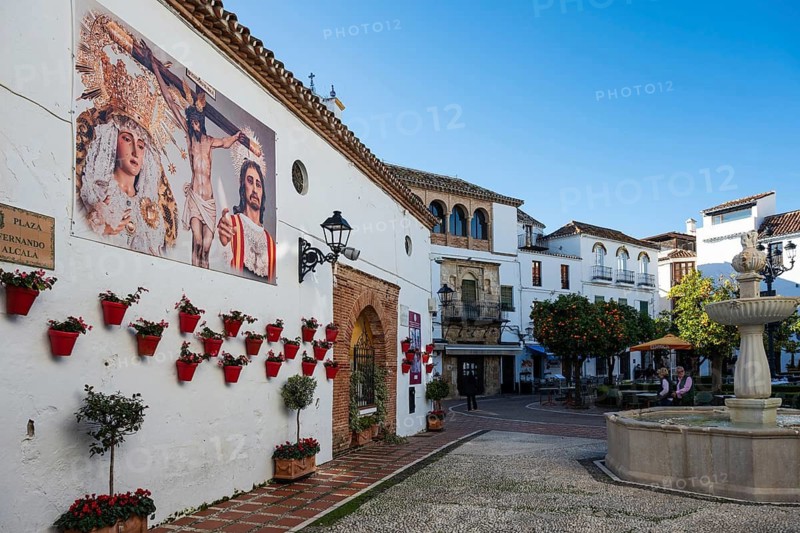 MARBELLA, SPAIN - JANUARY 31, 2026: Aerial view of a historic Spanish Plaza de los Naranjos with white buildings, orange trees, and a religious mural on the wall