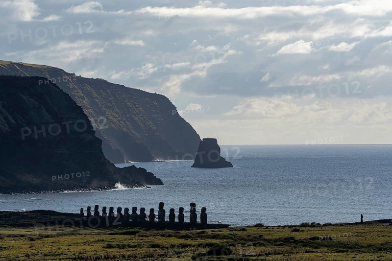 Moai statues of Ahu Tongariki in a row on the coast, behind steep cliffs and rock formation in the Pacific Ocean, Ahu Tongariki, Rapa Nui, Easter Island, Chile