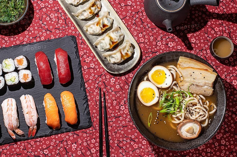 Top-down view of an elegant sushi dinner with a variety of Japanese dishes, shot in studio with hard light to enhance textures and details