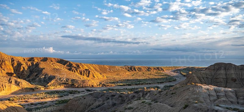 Landscape of eroded hills at sunrise, badlands, Issyk Kul Lake in the background, Canyon of the Forgotten Rivers, Issyk Kul, Kyrgyzstan
