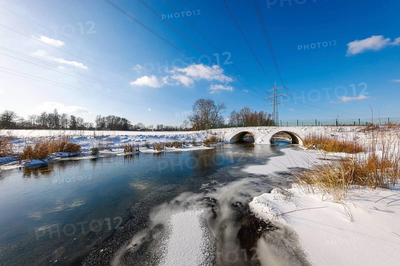 Bottrop, North Rhine-Westphalia, Germany - Sunny winter landscape in the Ruhr area, ice and snow on the renaturalised Boye, the small river is being renaturalised, is being transformed into a near-natural body of water, the Boye is part of the Emscher river system and thus part of the Emscher conversion, was previously an open, above-ground wastewater canal, mixed water canal with surface water and wastewater