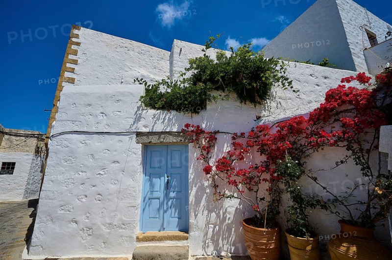 White house with blue door, red flower tendril, bright blue sky, Mediterranean atmosphere, Chora, main town Patmos, Patmos, old town, Dodecanese, Greek Islands, Greece
