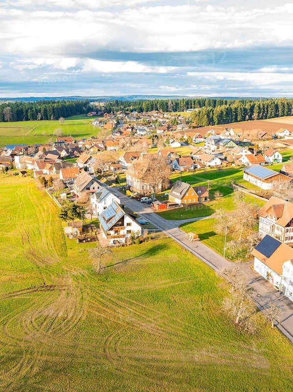 Rural village with scattered houses and green fields under a cloudy sky, Agenbach, Black Forest, Germany