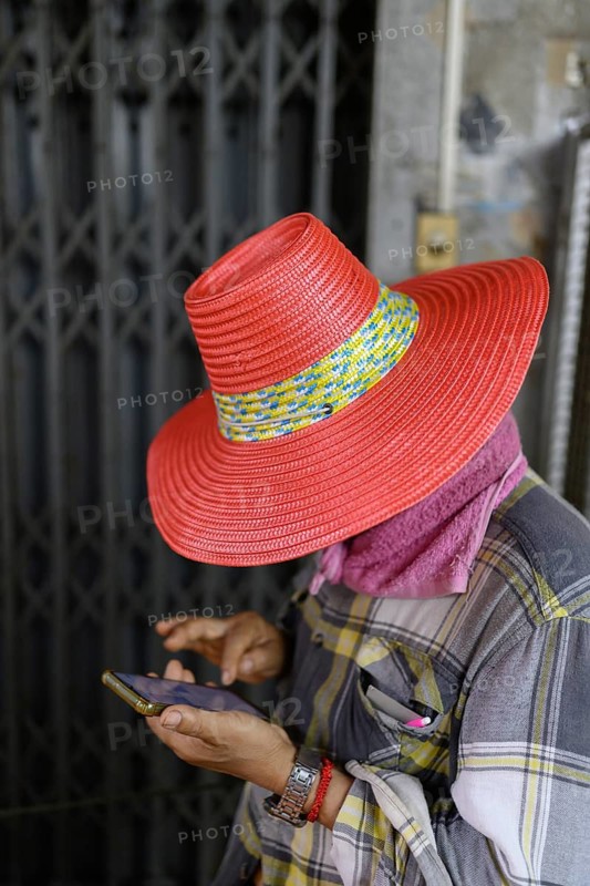 A local street vendor checks his phone in an alleyway near Yaowarat Road, Chinatown, Bangkok, Thailand, Yaowarat Road is the main artery of Bngkoks Chinatown, main centre of trading by the Chinese community for the last 200 years. Popular with locals and tourists, known as an exciting hub for its variety of restaurants and street food