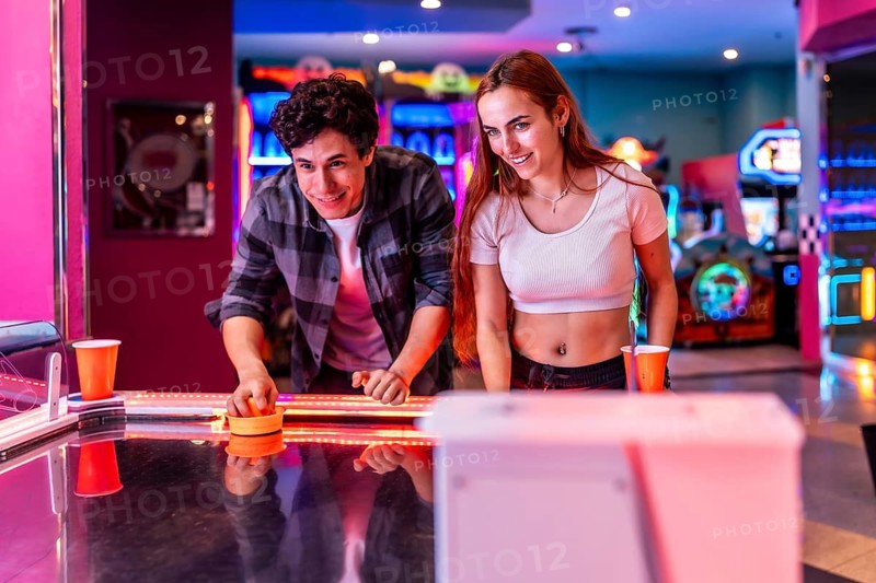 Young multiethnic friends enjoying a weekend together playing air hockey in an amusement arcade