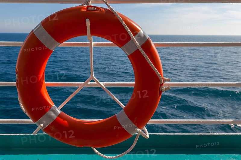 An orange-coloured lifebuoy hangs from a railing in front of a wide sea horizon, Norway