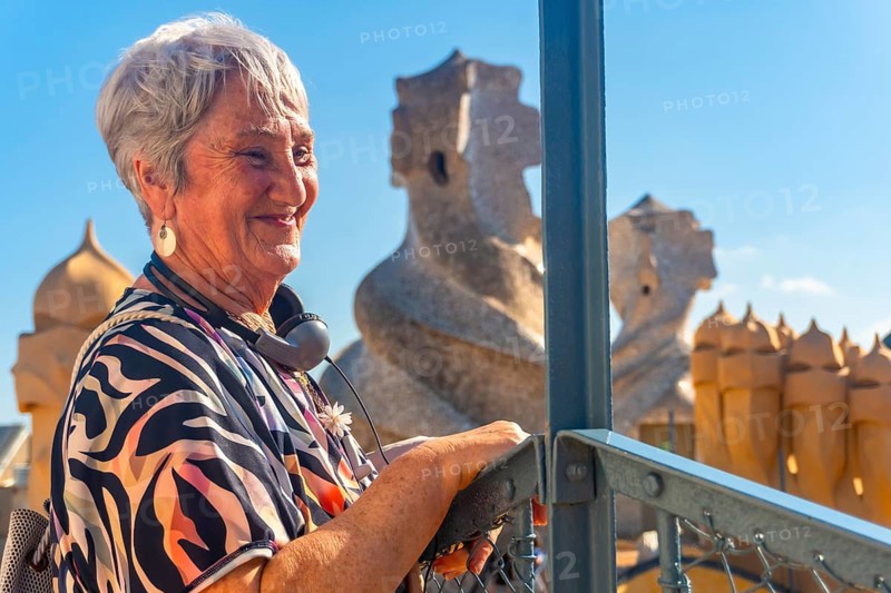 Elderly woman enjoying a guided tour of the whimsical chimneys on the rooftop of antoni gaudi's casa mila - la pedrera - in barcelona
