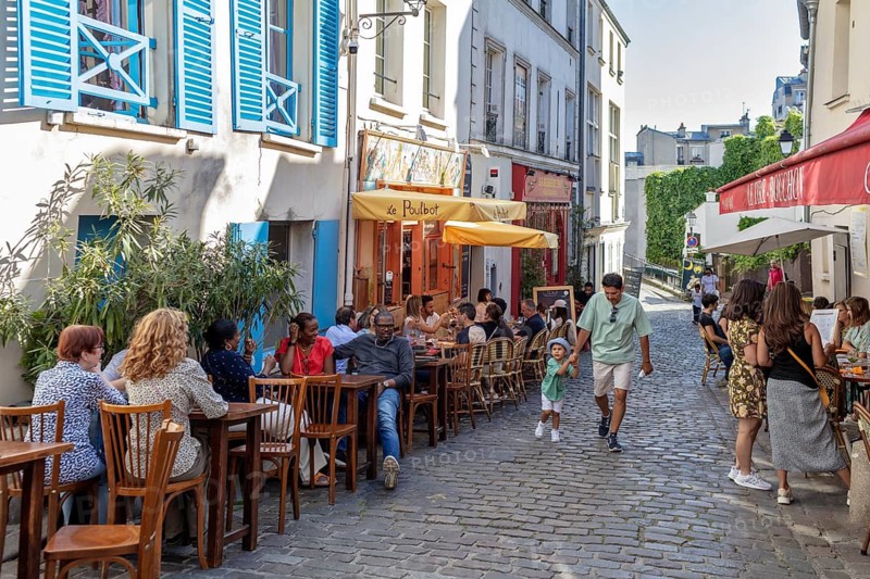 People enjoying a café outside on a cobbled village street, Paris