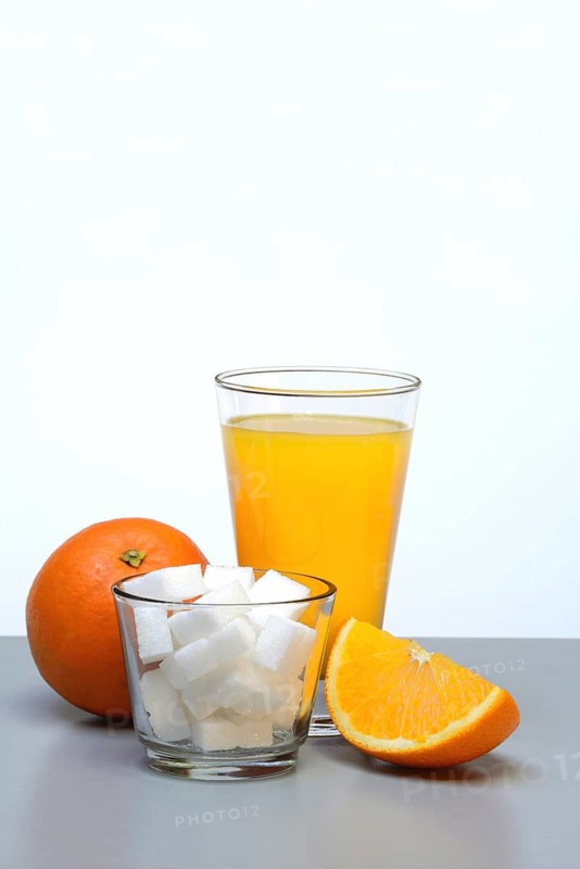 Orange juice in a drinking glass, half an orange and sugar cubes