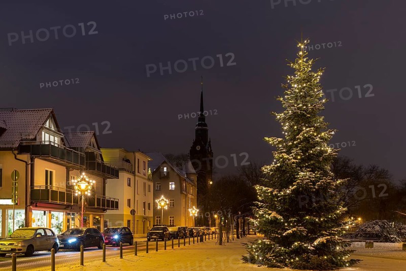 Christmas tree on the snow-covered Wettinplatz, in the background the New Church of St Peter and Paul, Coswig, Saxony, Germany