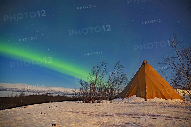 A tent in a snow-covered landscape with northern lights in the night sky, Abisko, Abisko National Park, Torneträsk, Lapland, Sweden