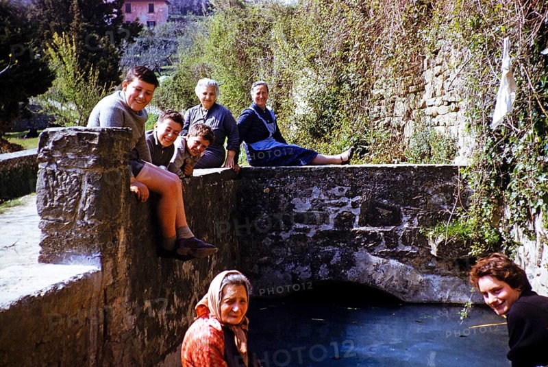 Woman and boys of an Italian family sitting on a bridge in a village, Italy 1957