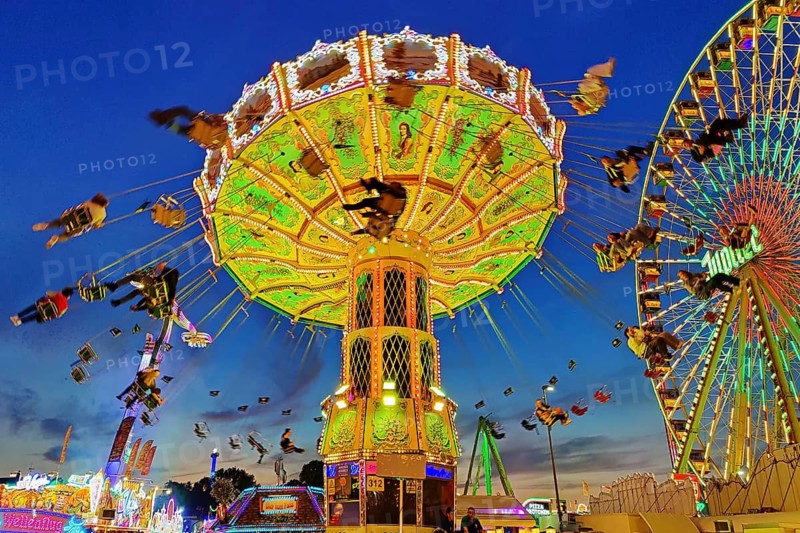 The colourfully illuminated Wellenflug chain carousel and the Ferris wheel in the evening, Cranger Kirmes, Herne, Ruhr area, North Rhine-Westphalia, Germany