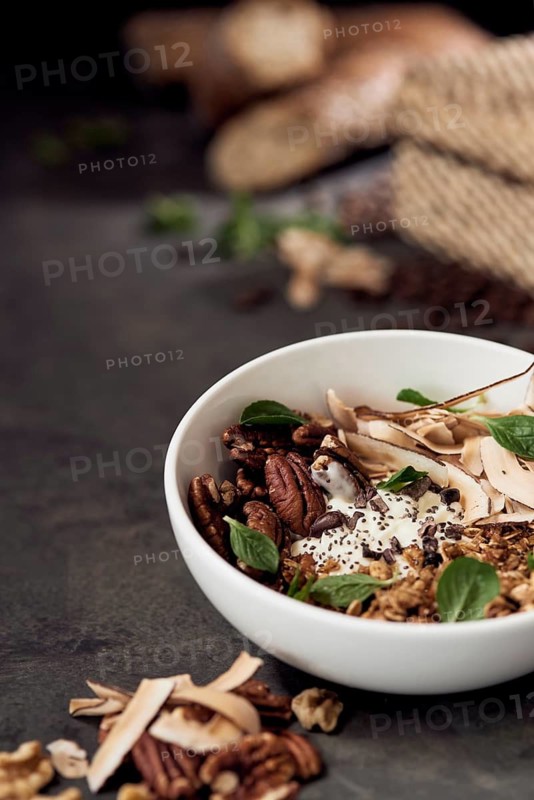 A nutritious breakfast natural bowl filled with pecans, walnuts, coconut flakes, and chia seeds, elegantly presented on a rustic wooden table for a wholesome start to the day