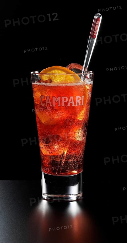 Cocktail Campari Orange Soda in a long drink glass in front of a black background, half an orange slice as garnish, studio shot